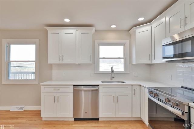 kitchen with visible vents, white cabinets, stainless steel appliances, and a sink