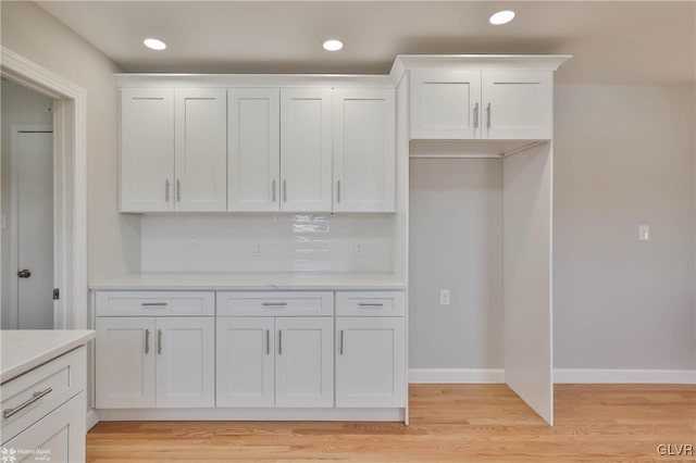 kitchen featuring light wood finished floors, white cabinets, light countertops, and baseboards