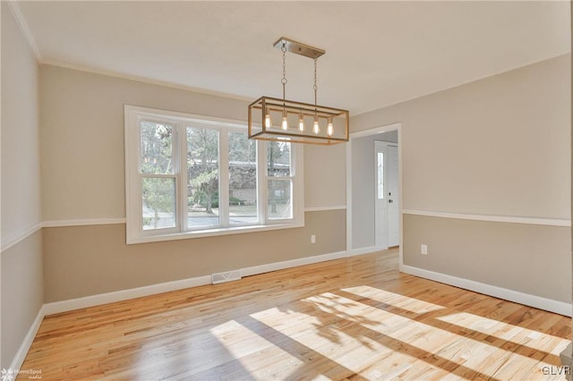 empty room featuring visible vents, baseboards, an inviting chandelier, and wood finished floors