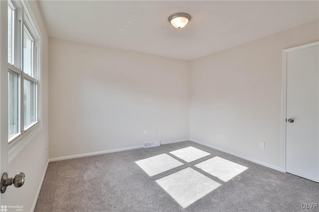 spare room with visible vents, baseboards, and carpet flooring