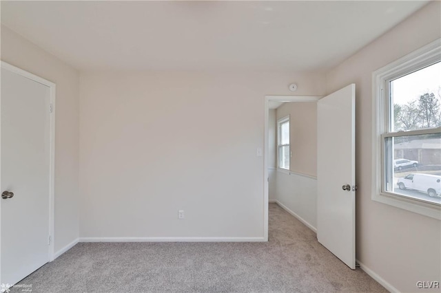 empty room featuring light colored carpet and baseboards