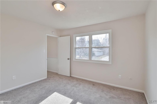 carpeted empty room featuring baseboards