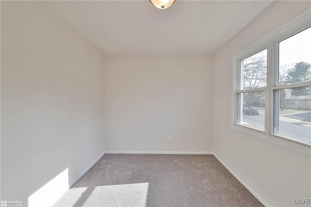 spare room with baseboards and carpet floors