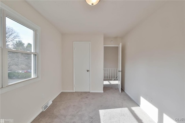 spare room with baseboards, visible vents, and light carpet