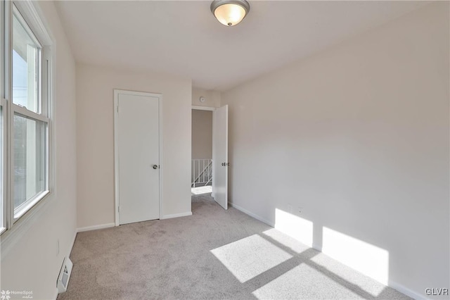 unfurnished bedroom featuring visible vents, light colored carpet, and baseboards