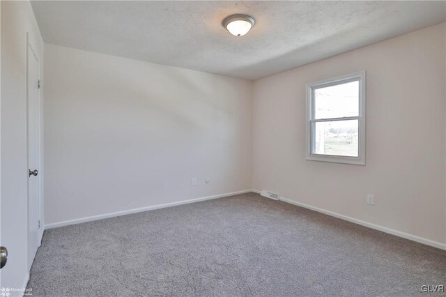 unfurnished room featuring carpet flooring, visible vents, baseboards, and a textured ceiling