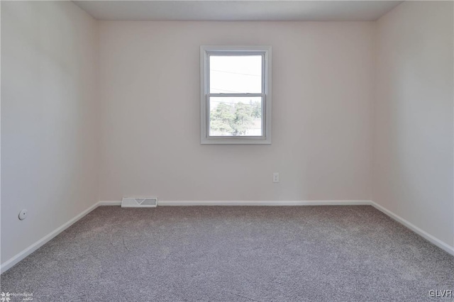 carpeted spare room with visible vents and baseboards