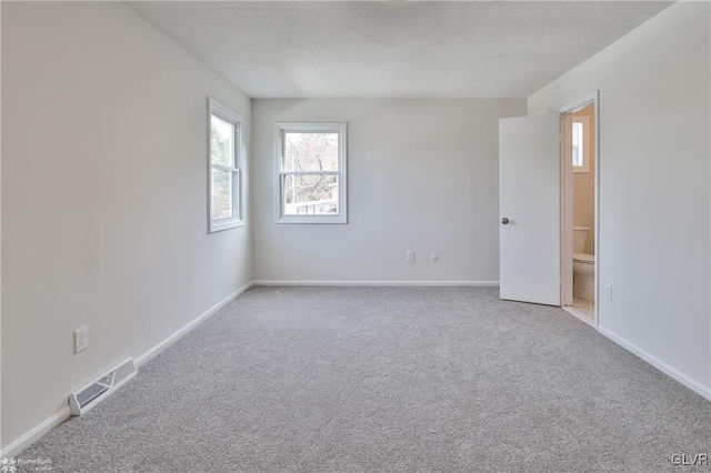 carpeted spare room with visible vents and baseboards