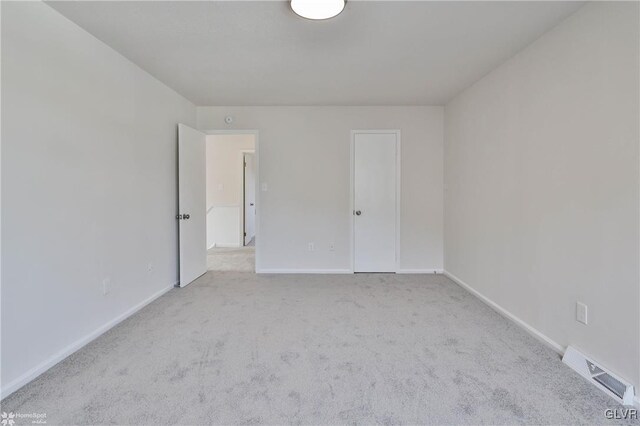 empty room featuring visible vents, carpet, and baseboards