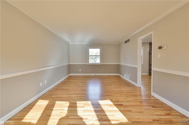 unfurnished room with visible vents, baseboards, light wood-style floors, and ornamental molding