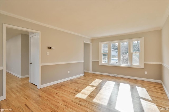 empty room with visible vents, baseboards, light wood finished floors, and ornamental molding