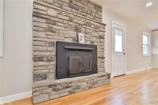 room details featuring recessed lighting, baseboards, a stone fireplace, and wood finished floors