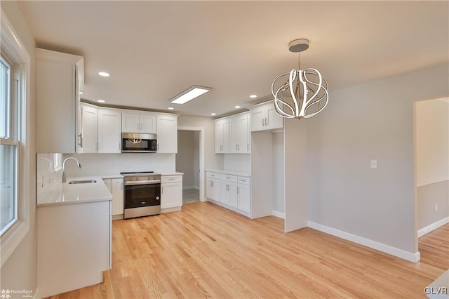 kitchen with a sink, appliances with stainless steel finishes, light countertops, and light wood finished floors