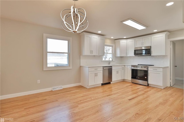 kitchen featuring visible vents, a chandelier, light countertops, appliances with stainless steel finishes, and white cabinetry