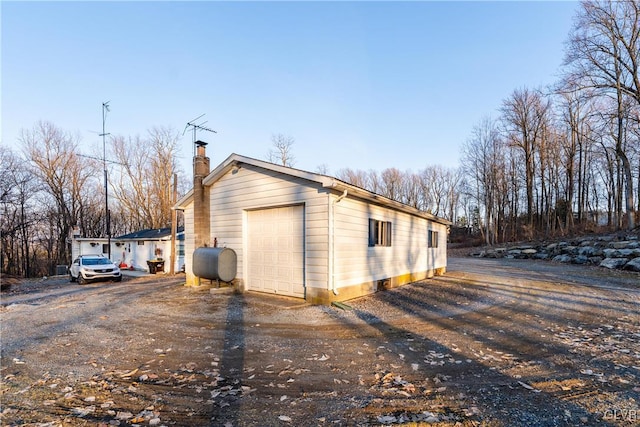 view of outbuilding with a garage, driveway, and heating fuel