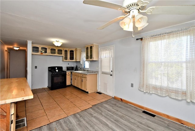 kitchen featuring a ceiling fan, light countertops, black gas range, light wood-style floors, and stainless steel microwave