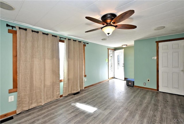 spare room with ceiling fan, visible vents, baseboards, and wood finished floors