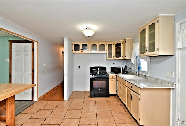 kitchen featuring black appliances, light tile patterned floors, glass insert cabinets, and a sink