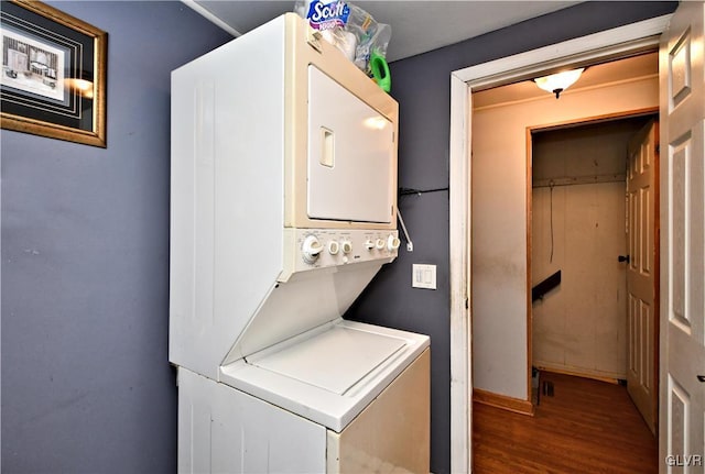 washroom featuring laundry area, stacked washing maching and dryer, baseboards, and wood finished floors