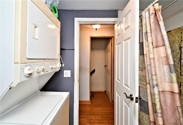 washroom with stacked washer and dryer, wood finished floors, and laundry area