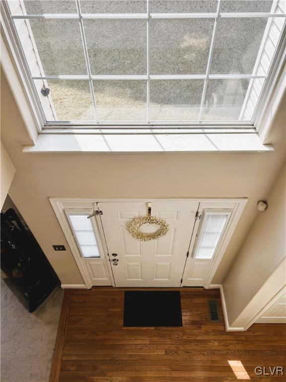 entrance foyer with a wealth of natural light, visible vents, baseboards, and dark wood finished floors