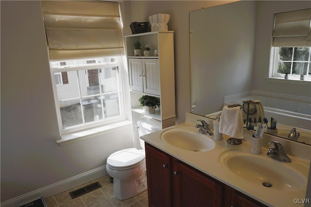 bathroom featuring a sink, visible vents, toilet, and double vanity