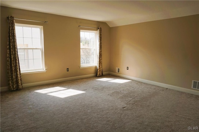 empty room with vaulted ceiling, carpet, baseboards, and visible vents