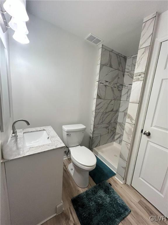 bathroom featuring visible vents, a stall shower, toilet, and wood finished floors