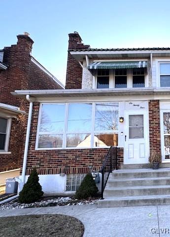 view of front of home featuring brick siding and a chimney