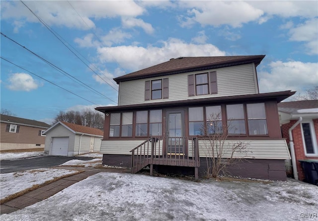 view of front facade featuring a detached garage, an outbuilding, driveway, and a sunroom