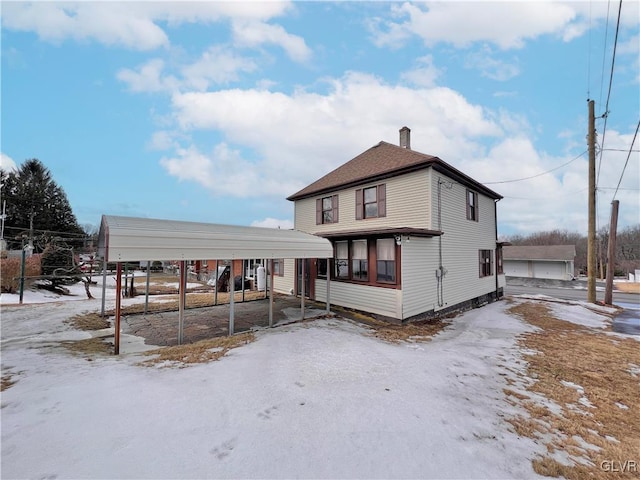 rear view of property featuring a detached carport and a chimney