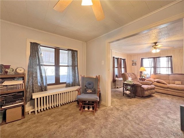 carpeted living room featuring radiator, crown molding, and ceiling fan