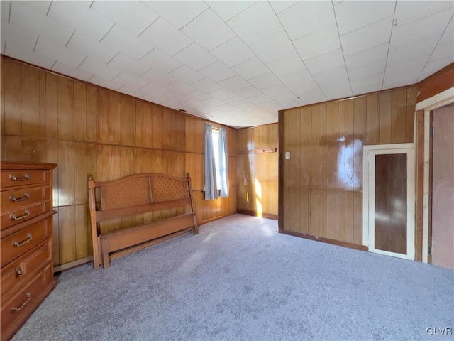 unfurnished bedroom featuring carpet and wooden walls