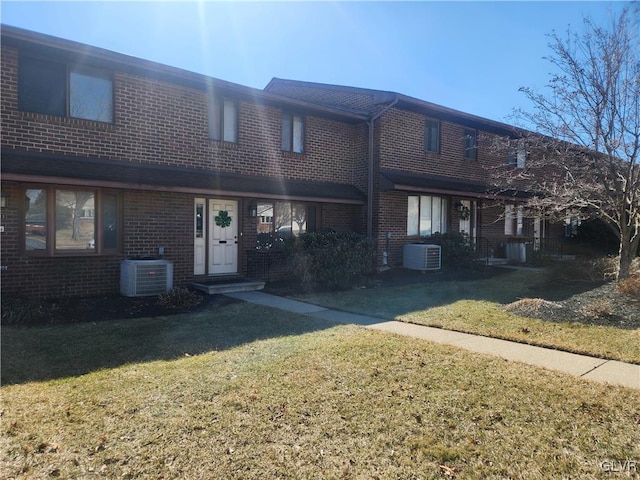 view of front of house with a front yard, central air condition unit, and brick siding