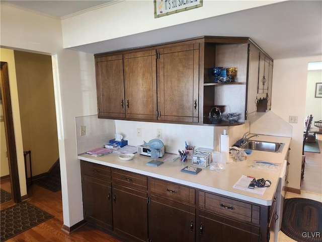 kitchen featuring dark wood finished floors, light countertops, dark brown cabinets, and a sink