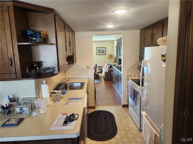 kitchen with white appliances, dark brown cabinets, light countertops, and a sink