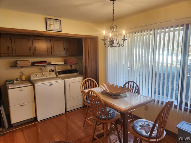 dining area featuring washing machine and clothes dryer, a notable chandelier, and wood finished floors