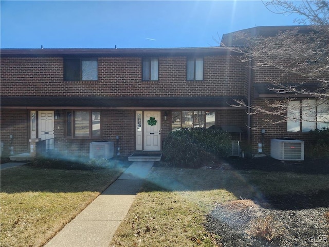 multi unit property featuring brick siding, central AC unit, and a front yard