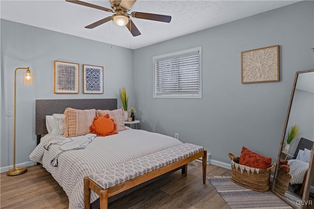 bedroom with a textured ceiling, a ceiling fan, baseboards, and wood finished floors