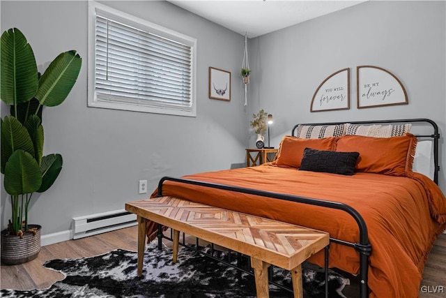 bedroom with baseboard heating, baseboards, and wood finished floors