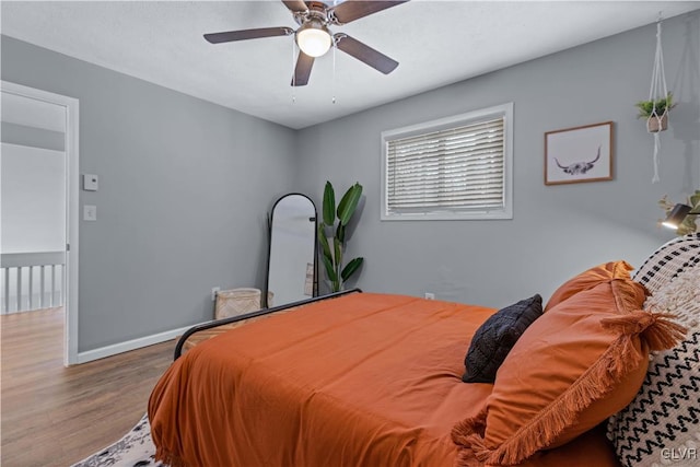 bedroom featuring ceiling fan, baseboards, and wood finished floors