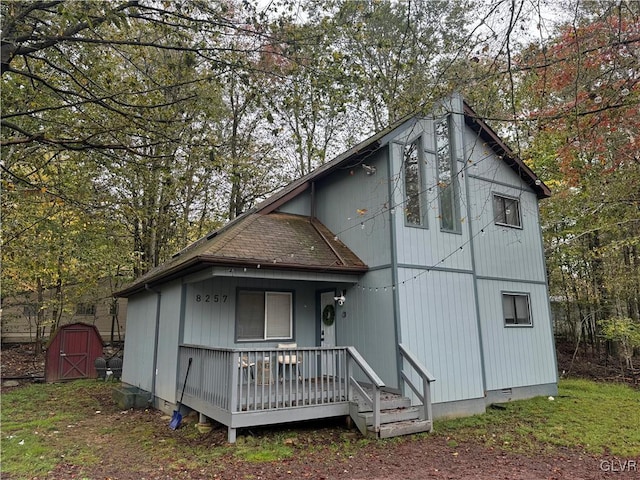 rear view of property featuring an outbuilding, a porch, and a storage shed