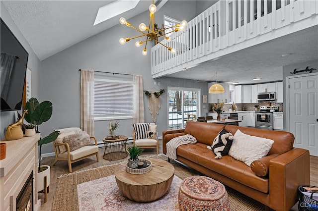 living area with wood finished floors, baseboards, a skylight, a towering ceiling, and a chandelier