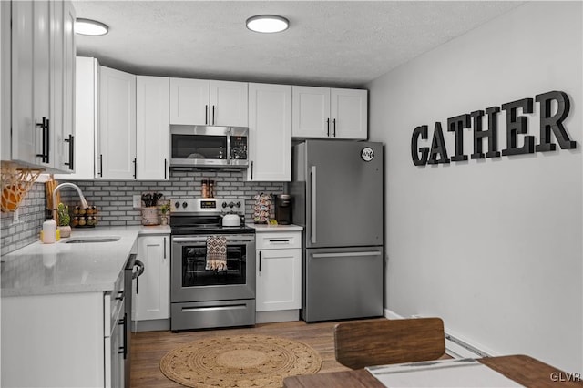 kitchen with a sink, white cabinetry, appliances with stainless steel finishes, and light countertops