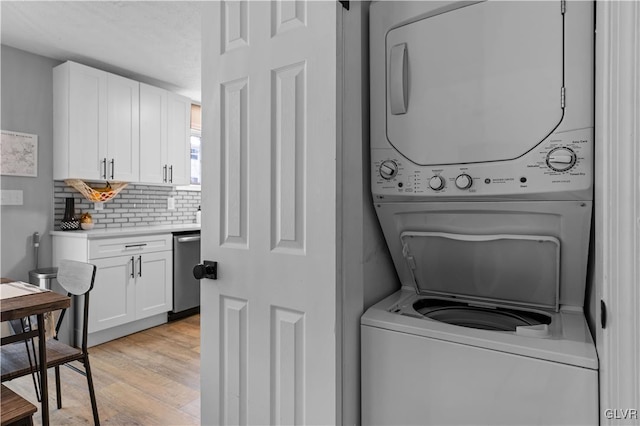 laundry area with laundry area, light wood finished floors, and stacked washing maching and dryer