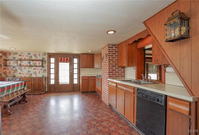 kitchen with a sink, light countertops, black dishwasher, brick patterned floor, and brown cabinets