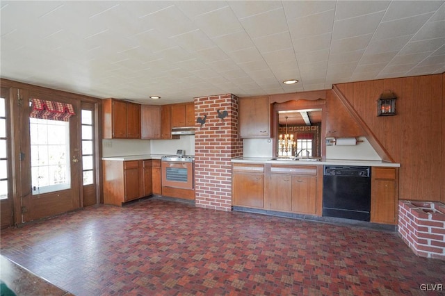 kitchen featuring under cabinet range hood, wood walls, stainless steel appliances, and light countertops