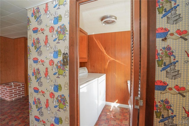 washroom featuring cabinet space, wood walls, and independent washer and dryer