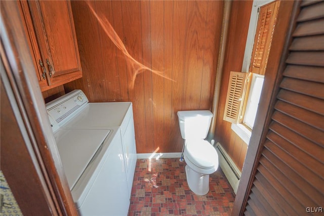 bathroom featuring wooden walls, washing machine and dryer, toilet, and a baseboard heating unit