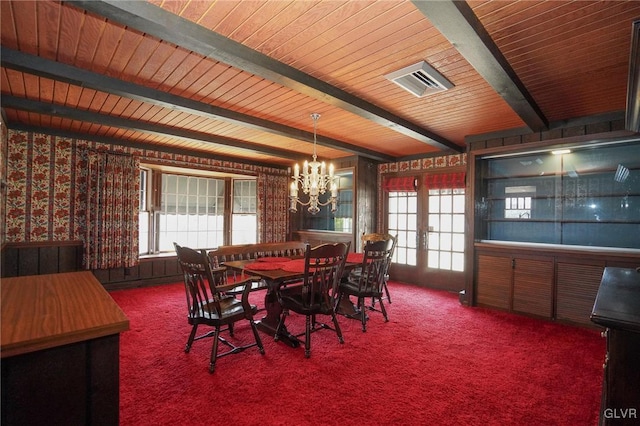 carpeted dining area with beam ceiling, french doors, and a chandelier